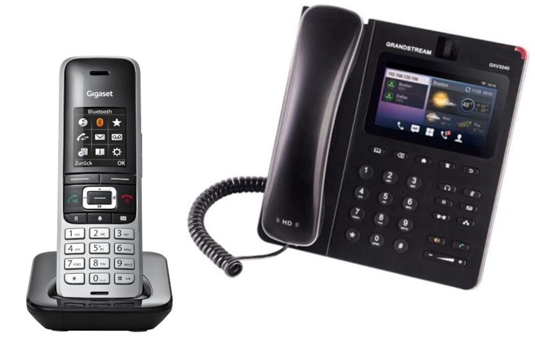 Telefon bezprzewodowy Gigaset w czarno-srebrnej obudowie na podstawce oraz czarny telefon stacjonarny Grandstream GXV3240 z kolorowym wyświetlaczem i słuchawką przewodową.